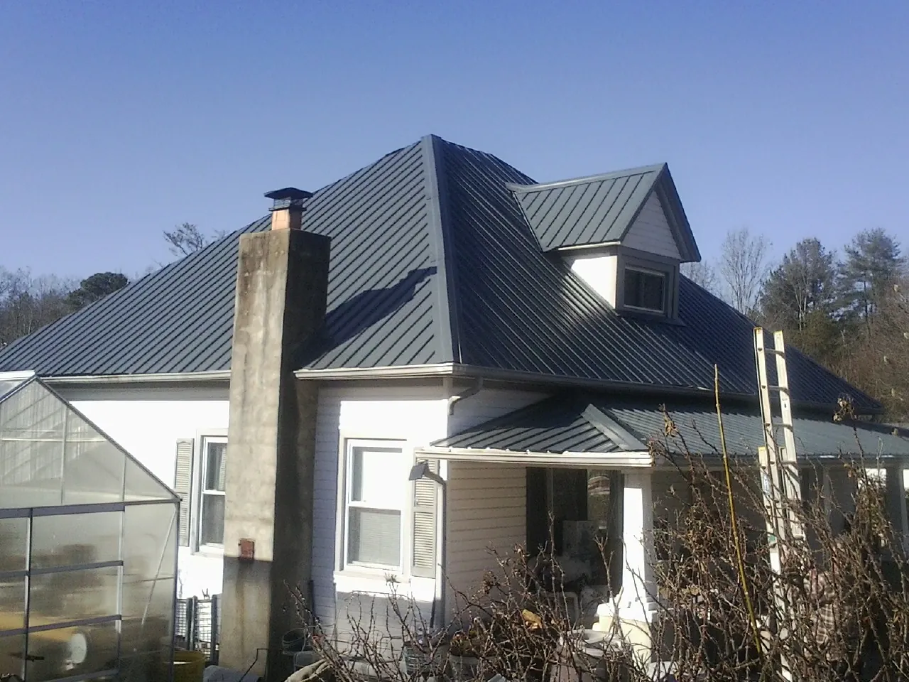 Dark blue standing seam metal roof on a white farmhouse with dormer — Slate & Tile Roof Repair by Roofing Brothers in Belcamp