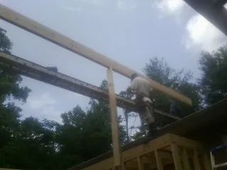 Carpenter setting a ridge beam over a new addition frame — Ice Dam Removal by Roofing Brothers in Belcamp