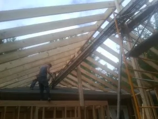 Rafters going up over a new addition with a worker on the wall in Belcamp