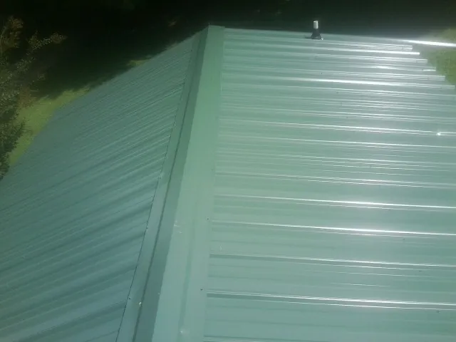 New green metal panels meeting at the ridge of a roof — Flat Roof Repair work by our crew in Belcamp