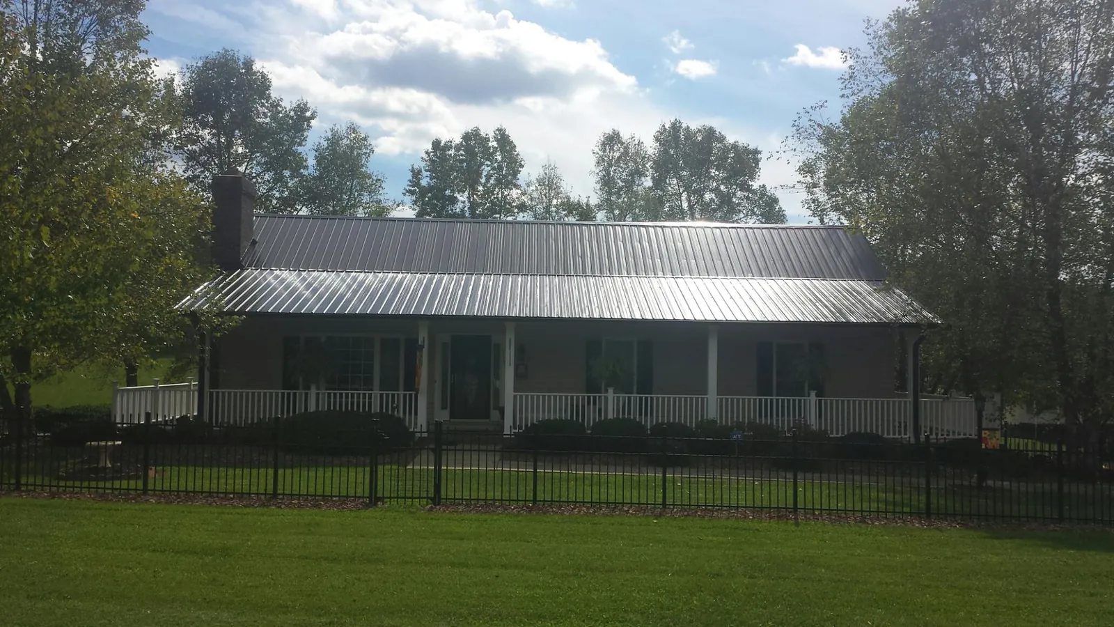 Gray metal roof on a brick ranch with a full width front porch — Gutter Guard Installation work by our crew in Belcamp