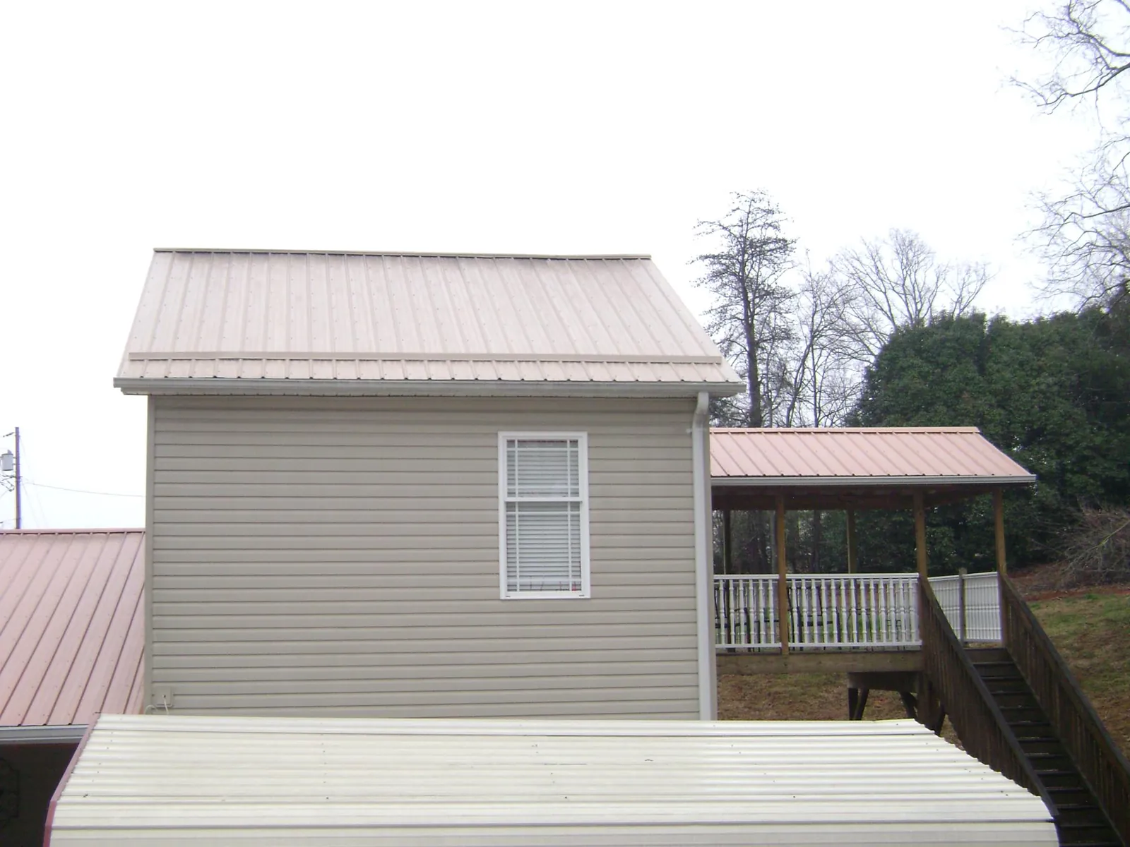 Tan metal roofs on a two story addition and attached porch, from a Roof Replacement job in Belcamp